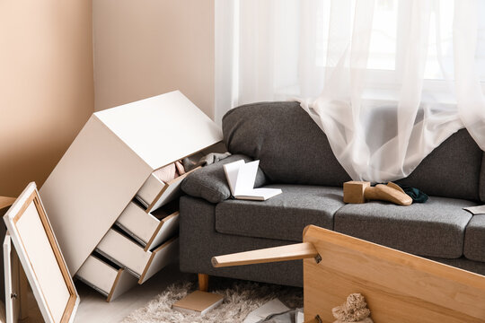 Interior of light living room with messed furniture after earthquake