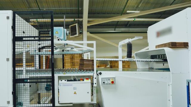 Silent highprecision equipment for folding and adhering cardboard components, White industrial apparatus used within contemporary factory for automated cardboard assembly processes