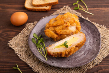 Chicken Schnitzel on gray plate with microgreen on brown wooden background and linen textile. side view, close up