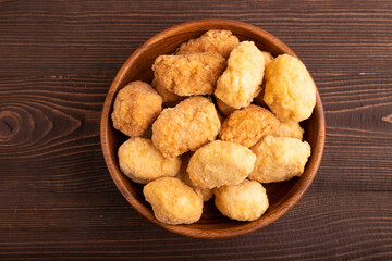 Fried crispy Chicken Nuggets on brown wooden. top view, copy space