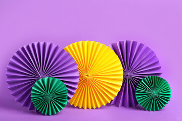 Colorful paper fans on purple background. Celebration of Mardi Gras