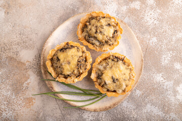 Tartlets with meat and cheese on brown concrete. top view, flat lay, copy space