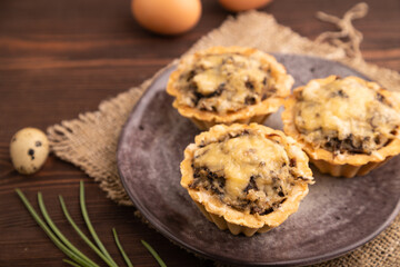 Tartlets with meat and cheese on brown wooden, linen textile. side view, close up, selective focus
