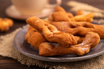 Crunchy biscuit Brushwood cookies on brown wooden, linen textile, cup of coffee, side view, close up, selective focus