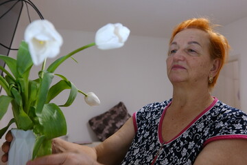 Happy adult woman hold flowers. Gift for holiday or birthday adult woman white tulips at home...