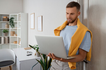 Young bearded man using laptop near door at home