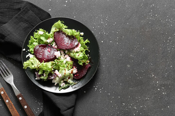 Plate of fresh salad with beet and cottage cheese on black background