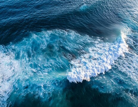 aerial view of ocean waves crashing with white foam on deep blue water creating dynamic sea patterns and textures