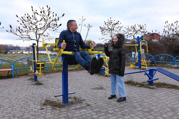 Outdoor sports ground. Free exercise equipment in public places. father and daughter walking in the...