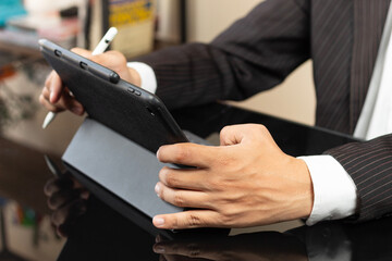 a male hands of a CEO on suit working at home on a tablet with a digital pen
