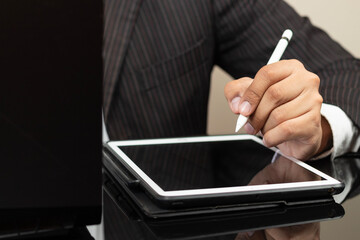 a CEO left hand holding a digital pen ready to draw something on a white tablet