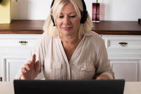Senior woman video calling using headset and laptop