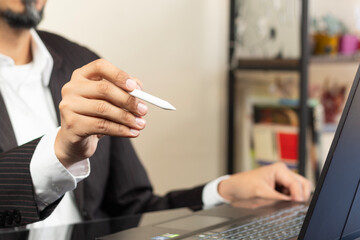 a CEO on suit working at home pointing with a white digital pen to something on the space at the left side of the screen