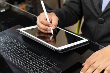 a male modern business man hands designing something over a white tablet and a black laptop