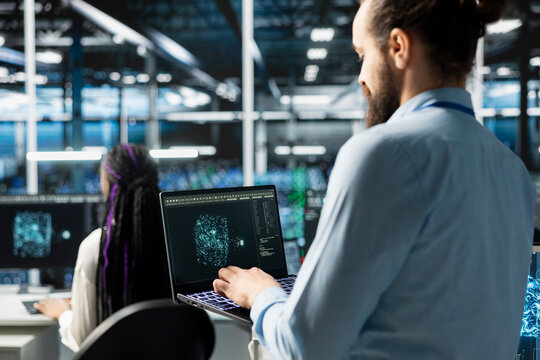 Software developer in data center using AI LLM assistant on laptop to perform maintenance on infrastructure rigs. Server hub IT expert using artificial intelligence large language model to do backups