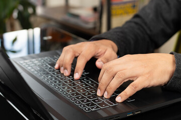 a male hands typing on a black laptop keyboard
