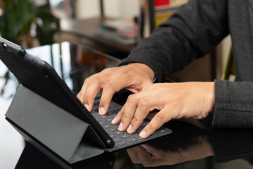 a male hands typing on a grey tablet keyboard