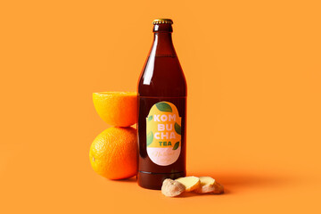 Bottle of tasty kombucha tea with orange and ginger on color background