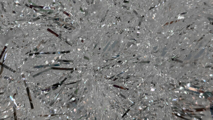 Shimmering silver tinsel strands create a sparkling background, reflecting light and adding festive ambiance, perfect for holiday decorations and celebrations