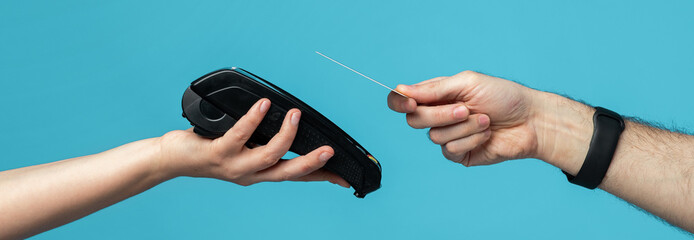A hand holds a card while another hand presents a card reader against a vibrant blue background. This scene showcases a contactless payment method in use, emphasizing convenience.