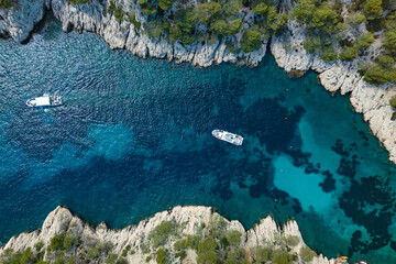 Excursion boats cruising in Calanques de Cassis, aerial view of scenic limestone cliffs and narrow...