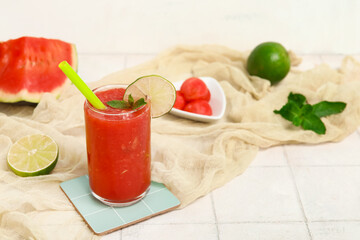 Glass of fresh watermelon juice with lime and mint on white tile table