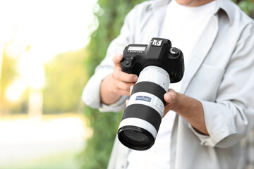 Male photographer with modern camera in park, closeup