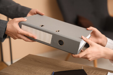 Young woman giving folder with documents in office. Closeup