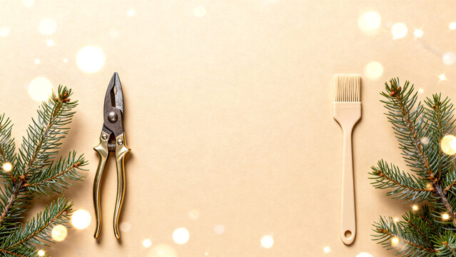 Christmas workshop composition with vintage pliers and brush on beige background framed by winter branches and lights, minimal festive tool layout, Copy Space