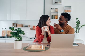 Interracial couple sharing coffee and smiles in kitchen