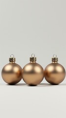 Three gold christmas ornaments in a row on a clean background. Vertical photo of minimalist festive holiday decorations with copy space for text