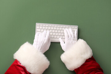 Santa Claus hands with keyboard on green background