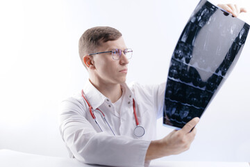 Caucasian male doctor analyzing analysis mri scan of spinal column in medical setting, white studio background