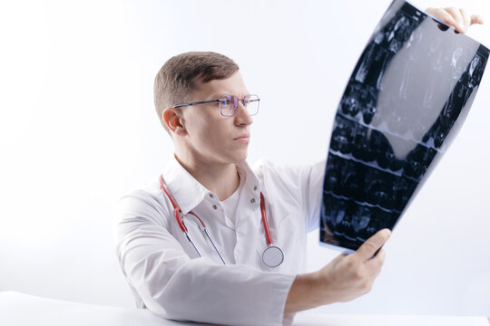 Caucasian male doctor analyzing analysis mri scan of spinal column in medical setting, white studio background