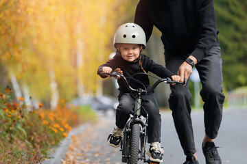 Father and little girl learning to ride bicycle park having fun together