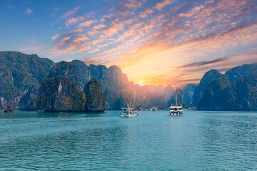 Scenic sunset over panorama Halong bay with limestone islands and boats, Vietnam