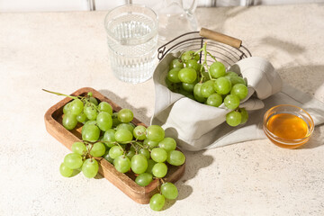 Wooden board and basket with sweet ripe grapes on white background
