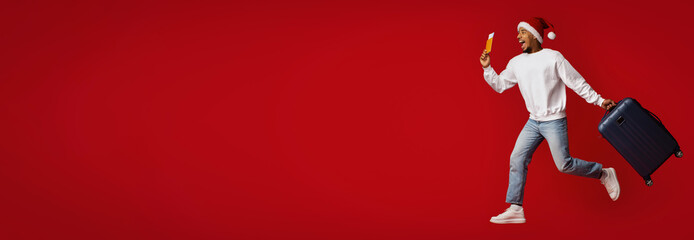 A joyful individual wearing a Santa hat is sprinting while holding a suitcase in one hand and a snack in the other. The vibrant red background enhances the holiday spirit and excitement.