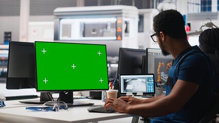 African american male engineer does troubleshooting on copy space display, fixing errors to ensure seamless solar panels manufacturing. Technician works in the assembly line. Camera A/ © DC Studio