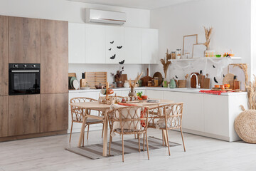 Interior of light kitchen decorated for Halloween with white counters and dining table