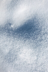 Dazzling close-up of glittering snow crystals. Textured winter surface with bright light and deep blue contrast. Icy background for cold concepts