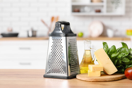 Grater, cheese and oil on table in kitchen