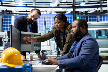 Multiethnic group of specialists with technical expertise share impressions, collaborating on industrial development in a solar panel facility. Overseeing sustainable energy production.