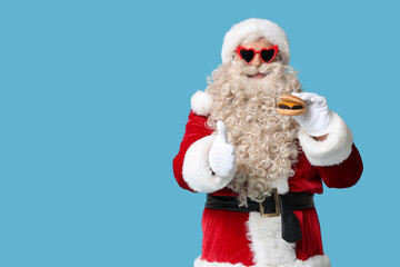 Santa Claus with tasty burger showing thumb-up on blue  background