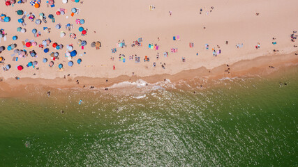 Aerial view of vibrant beach scene with colorful umbrellas and sunbathers enjoying sunny day by the ocean, capturing summer leisure atmosphere. Tavira Portugal Algarve