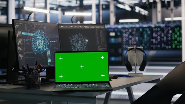 Chroma key notebook and PCs in high tech data center workspace used for AI system monitoring and performance tracking. Mockup notebook overseeing server racks involved in computing operations