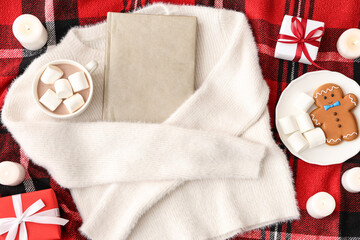 Obraz premium Composition with book, warm sweater, cup of cocoa drink and burning candles on red checkered plaid