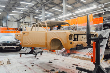 Specialist spraying anti rust sealant into the hidden chassis cavities. Protection against corrosion and internal body element sealing in a professional auto service shop