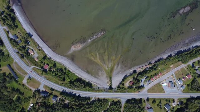 Aerial view from over 500m altitude of L'Anse du Petit Mitis and Pointe Mitis on the St. Lawrence River with its transparent water revealing the ocean floor. Quebec, Canada, 2025.