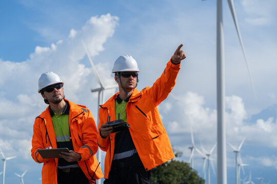 Field engineers examine wind turbine layout plans amid open-air wind power sources, symbolizing collaboration, safety, and renewable energy.